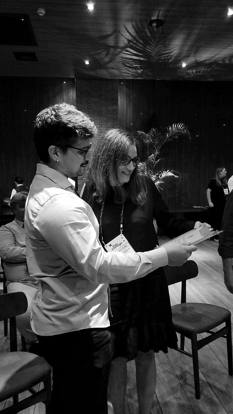 Participantes revisando material em dupla durante o Dale Carnegie Course